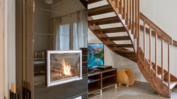 Una sala moderna con chimenea, una escalera de madera y una televisión.