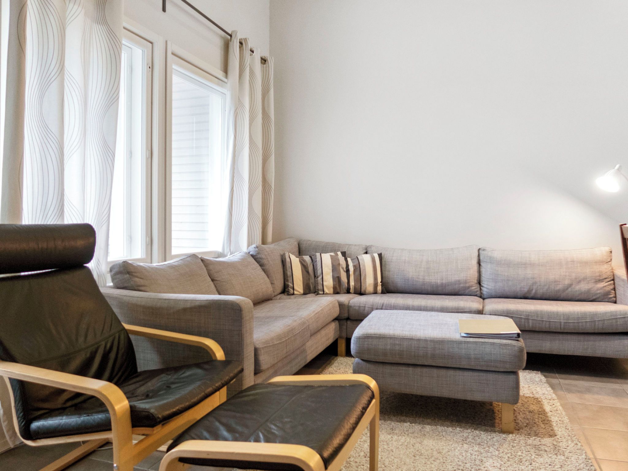 A living room with a sectional sofa, a leather armchair, and a small ottoman.