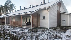 Una casa de un piso con techo inclinado, un porche cubierto y una chimenea.