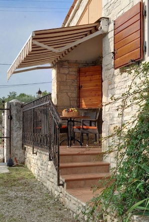 Enjoy dining or socializing in the covered outdoor seating area with a table and chairs.