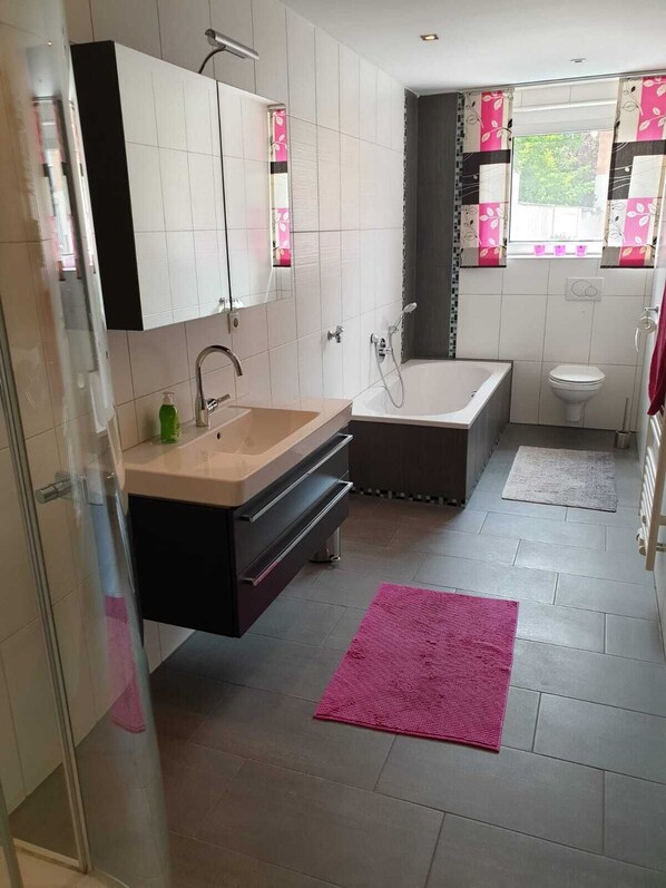 A modern bathroom with a bathtub, toilet, and sink.