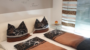 Een net opgemaakt bed met gestreepte kussens en een decoratief object aan de muur.