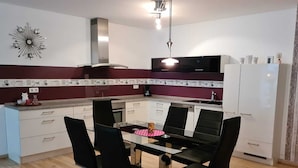 Een moderne keuken met een eettafel, vier stoelen, een koffiezetapparaat en een koelkast.