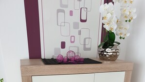 Een klein houten kastje met een glazen deurtje, een rode kaars en decoratieve voorwerpen erbovenop.