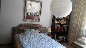 A bedroom with a bed, a bookshelf, a mirror, and a hanging light fixture. - 1 room apartment, ground floor, in the 2 Fam.House with garden, GE.-Buer (Gelsenkirchen-Buer, Gelsenkirchen)