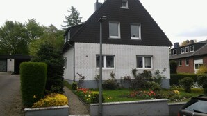 A two-story house with a sloped roof, white brick exterior, and two windows. - 1 room apartment, ground floor, in the 2 Fam.House with garden, GE.-Buer (Gelsenkirchen-Buer, Gelsenkirchen)