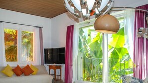 A living room with a sofa, a coffee table, and a TV. There is a sliding glass door with a view of greenery outside. - Vista Valle by Interhome (Castro)