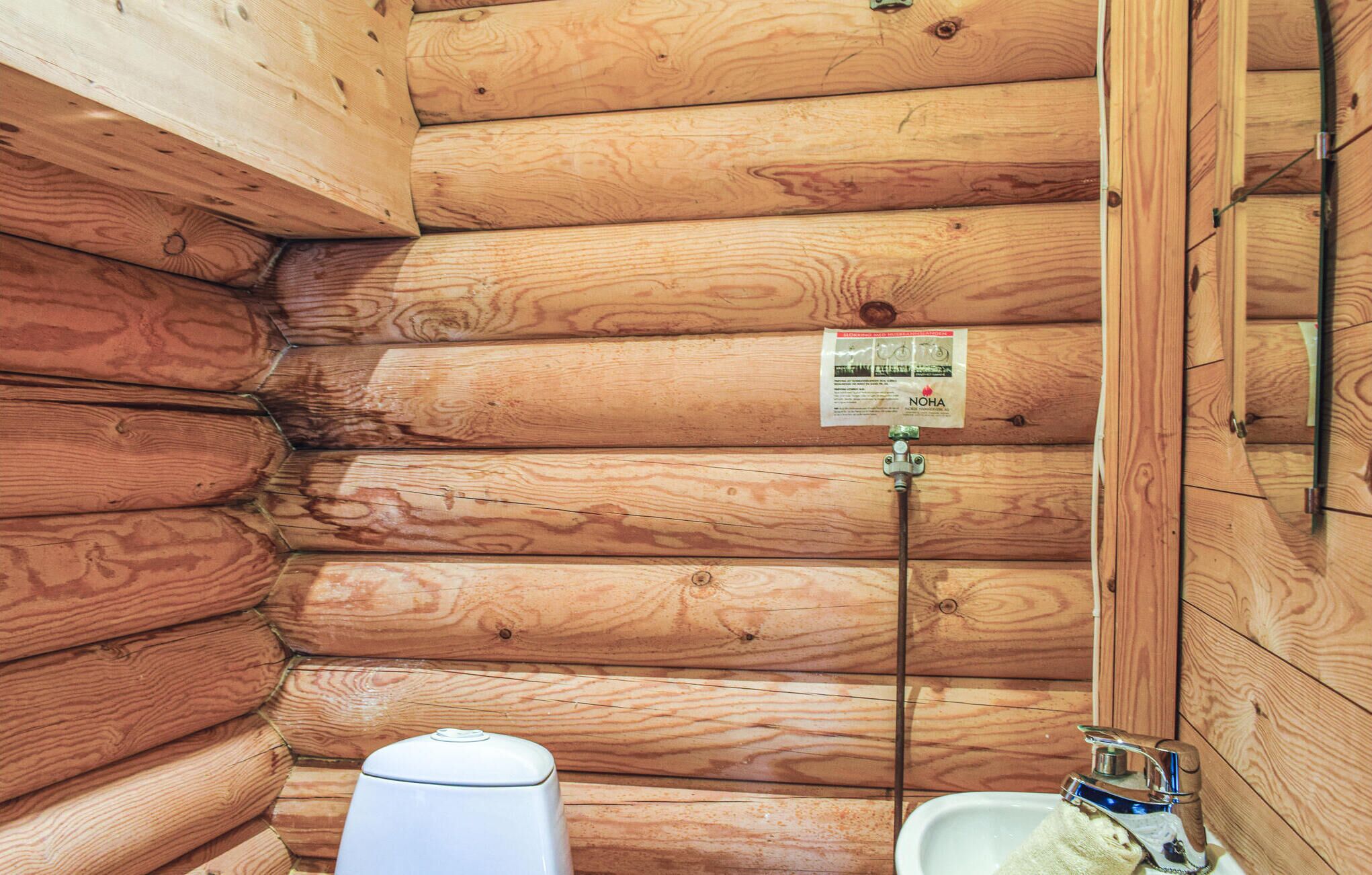 Un baño de cabaña de madera con inodoro, lavabo y ducha.