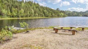 Ein Picknickplatz am Seeufer mit Bänken und einem Boot.