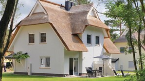 A house with a steeply pitched roof and a large front porch. - Reetdachhaus 20 auf Usedom (Zirchow/Usedom)
