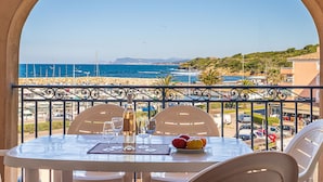 A table with a view of the sea and beach, white chairs, and a bottle of wine. - Les Rivages de Coudoulière by Interhome (Six Fours La Coudoulière)