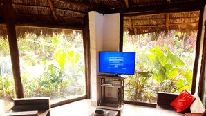 Una habitación con televisión sobre un mueble de madera, una mesa de centro y dos sillas.