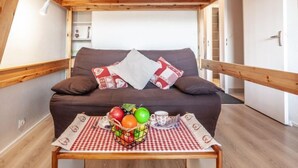A cozy room with a brown sofa, a checkered tablecloth, and a fruit basket with apples, oranges, and grapes. - Pegase Phenix by Interhome (Le Corbier)