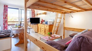 A cozy room with a bunk bed, a desk with a computer, a TV, and a dining area. - Pegase Phenix by Interhome (Le Corbier)