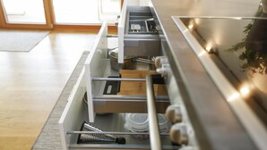 A kitchen with a stainless steel countertop, a built-in oven, and a drawer organizer with utensils. - Modern apartment with garden (Klaus)