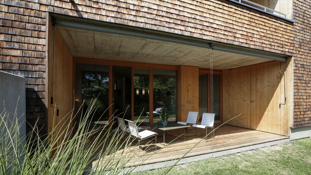 A modern building with a large open patio area featuring outdoor seating and a sliding glass door entrance. - Modern apartment with garden (Klaus)