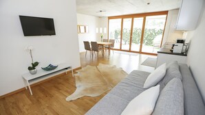 A modern living room with a sofa, a dining table, and a kitchen area. - Modern apartment with garden (Klaus)