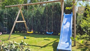Un parque infantil con tobogán, columpios y una escalera.