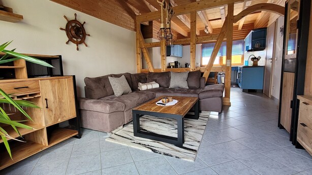 Una sala acogedora con un sofá seccional, armarios de madera y una mesa de comedor.