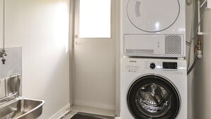 A compact laundry room with a front-loading washing machine, a stainless steel sink, and a small window. - Amazing home in årjäng with WiFi (Årjäng)