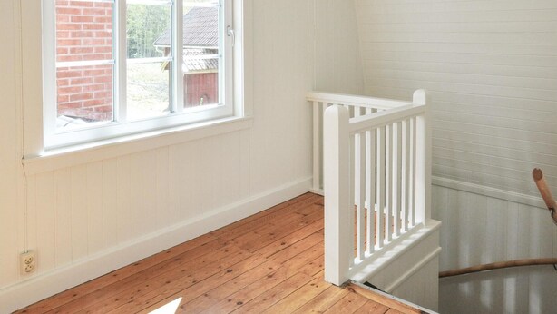 A room with a wooden floor, white walls, a window with a view of a brick building, and a white railing. - Amazing home in årjäng with WiFi (Årjäng)