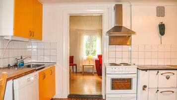 A kitchen with white and orange cabinets, a stove, and a sink.