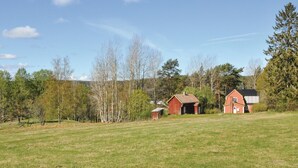 A rural landscape with a red barn, a small wooden structure, and a larger red building with a black roof. - Amazing home in årjäng with WiFi (Årjäng)