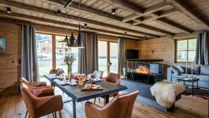Une pièce chaleureuse avec un plafond en bois, une cheminée, une table à manger avec des chaises et un canapé.