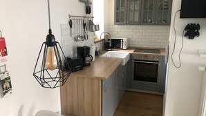 Uma cozinha compacta com bancada de madeira, forno embutido, micro-ondas e pia.