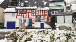 Uma casa tradicional em estilo de enxaimel com uma porta azul e degraus que levam à entrada principal.