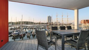 A balcony with a table and chairs overlooking a marina with boats and a tall ship. - Passatvilla - Apartment 3 (Travemünde-Waterfront)