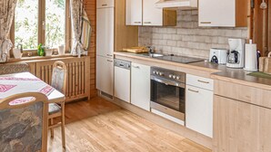 A compact kitchen with white cabinets, a built-in oven, a dishwasher, and a coffee maker. - Ferienwohnung in Fresach (Fresach)