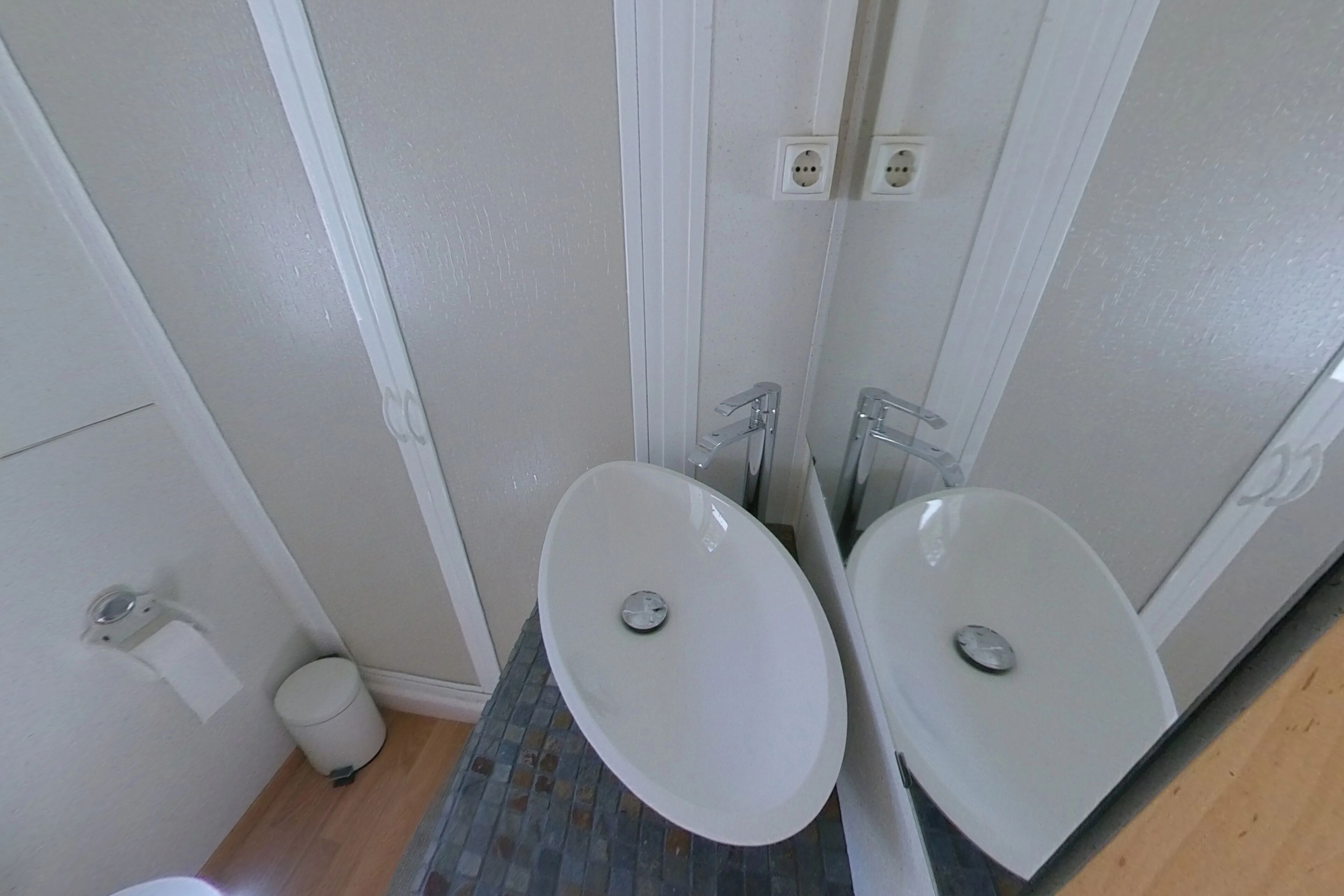 Une salle de bain avec deux lavabos, des toilettes et une poubelle.