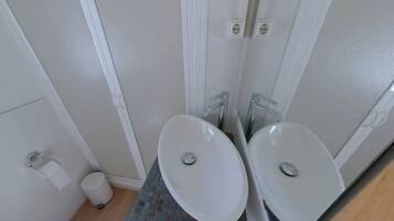 Une salle de bain avec deux lavabos, des toilettes et une poubelle.