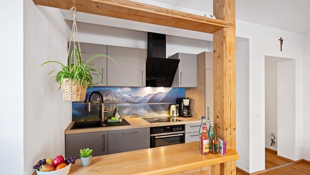 Une cuisine moderne avec un plan de travail en bois, un robinet noir, une machine à café et une bouteille de Coca-Cola.