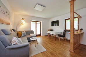 Relax in this spacious living area with a sofa set, dining table, and mounted TV.