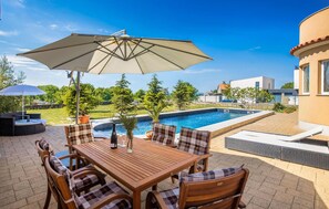 Relax by the pool in a serene outdoor space with a shaded patio, comfortable seating, and beautiful views.