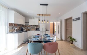 Enjoy a modern kitchen and dining area with a central island, oven, and glass-top table.