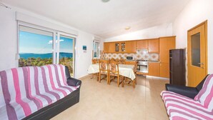 A living room with a sofa and armchairs, a dining area with a table and chairs, a kitchen with wooden cabinets and appliances, and a balcony with a view. - Beautiful apartment in Seget Vranjica (Seget Vranjica)