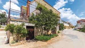 A two-story house with a balcony, stone facade, and a garden in front. - Beautiful apartment in Seget Vranjica (Seget Vranjica)