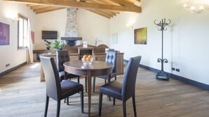 A spacious dining area with a wooden ceiling, a stone fireplace, and a modern TV. - Agr. Castello della Mugazzena by Interhome (Aulla)