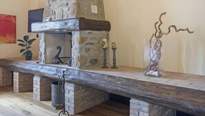 A stone fireplace with a wooden mantel, a hanging plant, and a decorative vase. - Agr. Castello della Mugazzena by Interhome (Aulla)