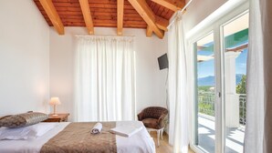 A bedroom with a bed, a chair, a TV, and a balcony with a view. - Beautiful home in Zrnovnica-Split with sauna (Zrnovnica-Split)