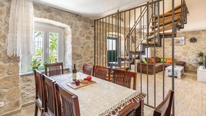 Zona pranzo con parete in pietra, una scala e vista all'esterno.
