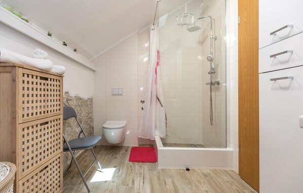 A modern bathroom with a shower, toilet, and a wooden cabinet with towels. - Cozy home in Ploce with house a panoramic view (Ploce)