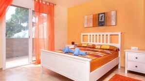 Ein Schlafzimmer mit Bett, Nachttisch und Blick durch eine Schiebetür.