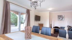 Ein modernes Wohnzimmer mit einem Holzesstisch, blauen Stühlen, einem Fernseher und einem Sofa.