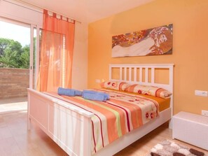 Quarto com cama, janela com cortinas, pintura na parede e vista para o verde lá fora.