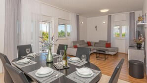 A modern living room with a grey sofa, a dining table set for four, and a small coffee table.