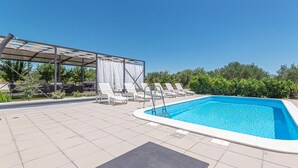 A swimming pool with lounge chairs and a covered seating area.